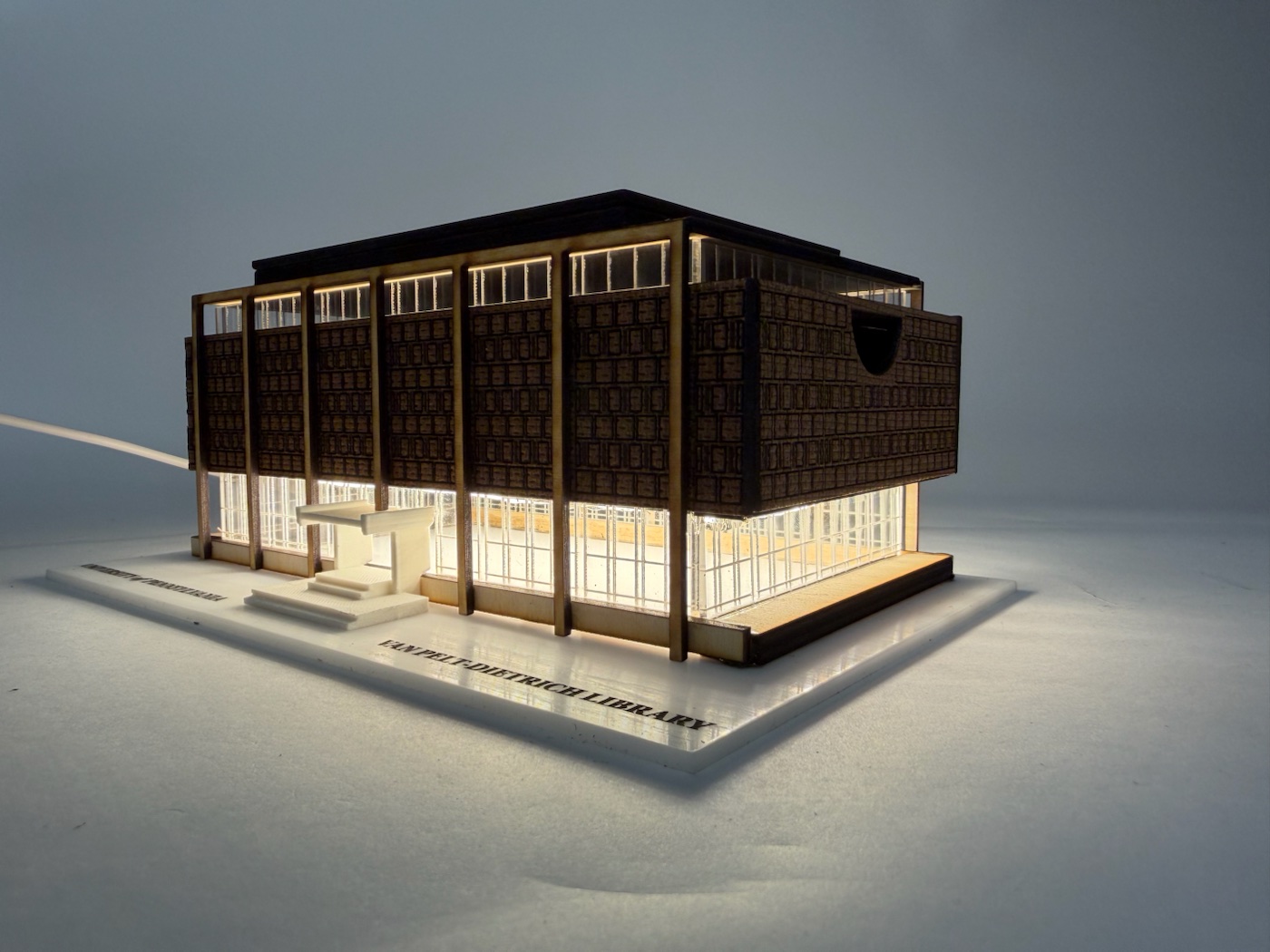 Illuminated Van Pelt Library box viewed from the front-right, with warm light glowing through its acrylic windows